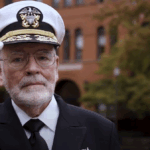 Bill Center salutes in front of Parrington Hall