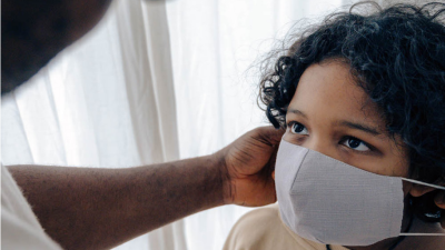 Adult touches face of child wearing mask