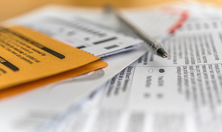 Vote by mail ballot, envelope and pen on table