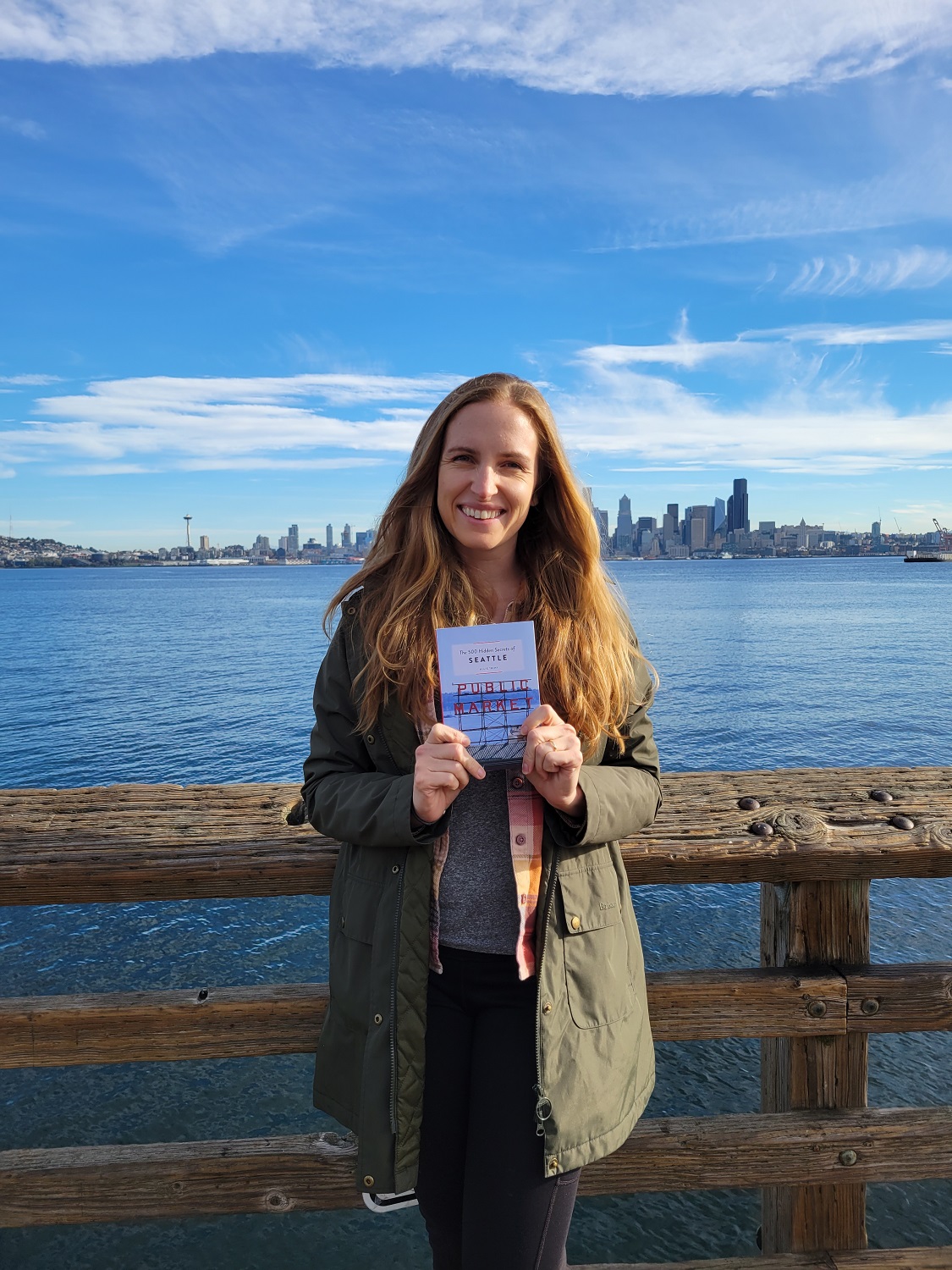 Allie Tripp holding her new book with the Seattle skyline in the background Allie Tripp holding her new book with the Seattle skyline in the background