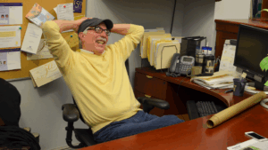 Pat Dobel wearing baseball cap leaning back in chair and smiling
