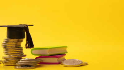 Graduation cap sits on stack of change next to globe and books