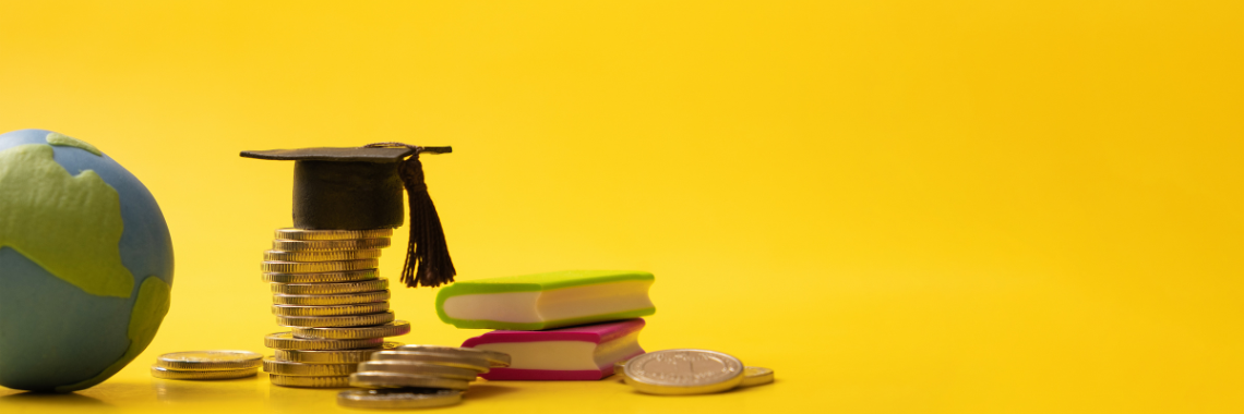 Graduation cap sits on stack of change next to globe and books