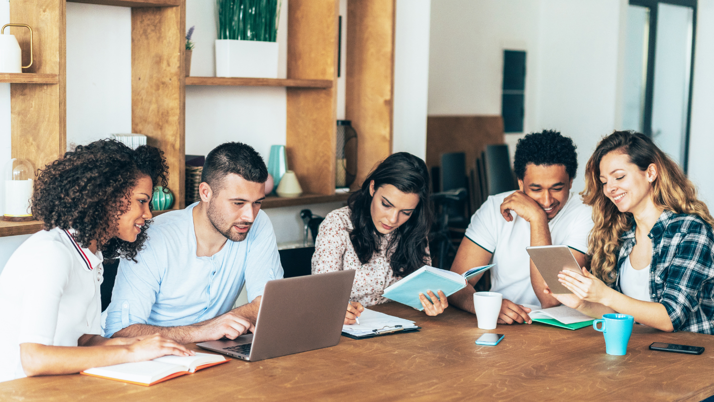 Five students sit around a table studying