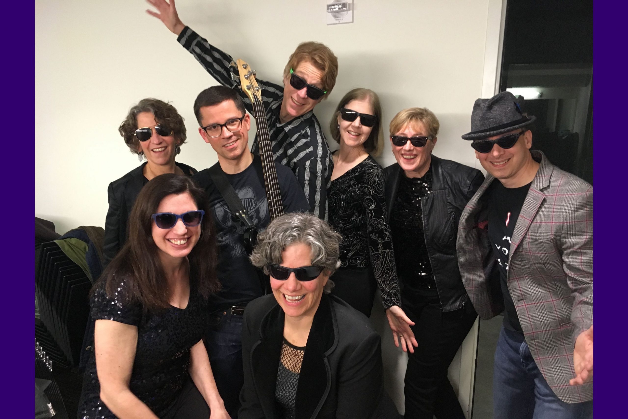 Eight members of the Evans School faculty band pose wearing sunglasses and black outfits