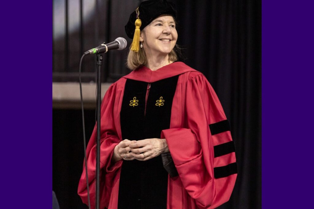 Alison Cullen in Doctoral Robes Alison Cullen stands at microphone wearing her doctoral robes