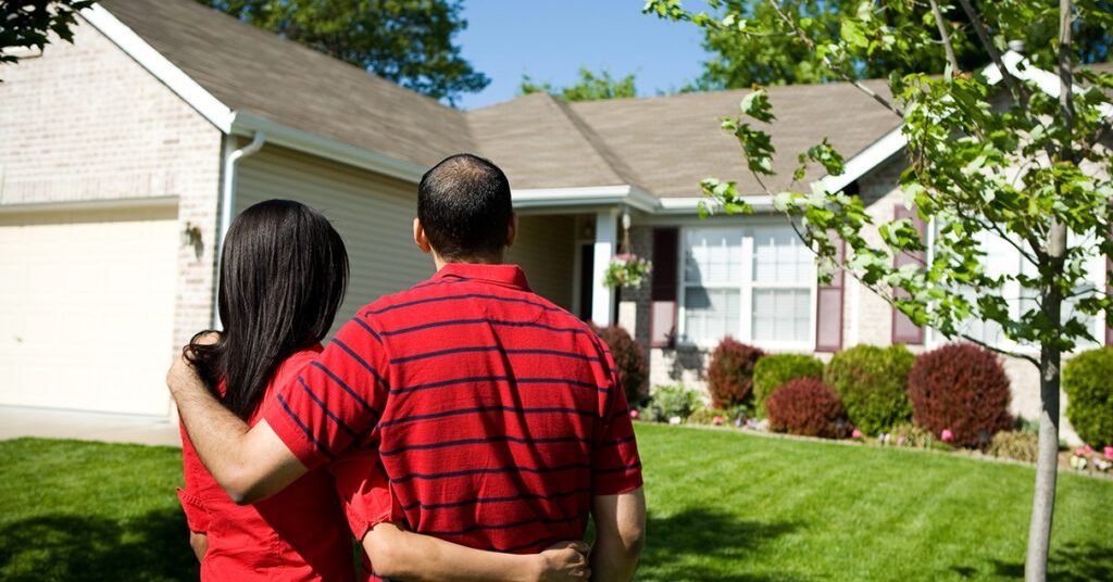 Two people standing outside a suburban single family home
