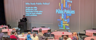 Students sitting at checkered tables watching a presentation at Public Policy Camp 2025