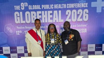 Three IPPHL alums stand in front of a banner with the works Globeheal 2026.