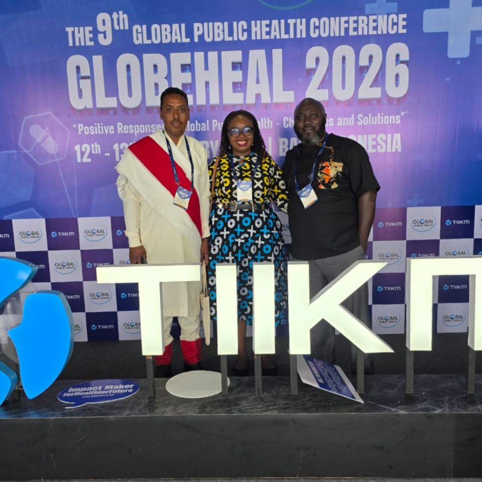 Three IPPHL alums stand in front of a banner with the works Globeheal 2026.