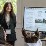 Two NextGen SPA students stand next to a screen with their presenation
