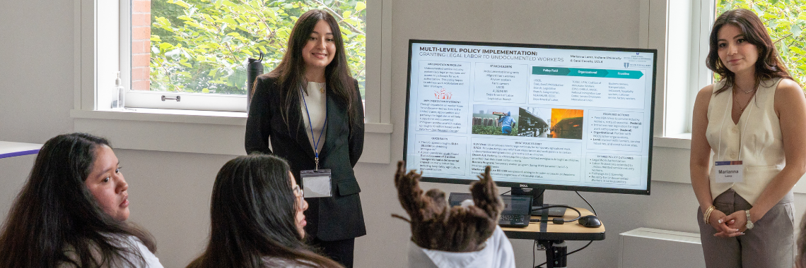 Two NextGen SPA students stand next to a screen with their presenation