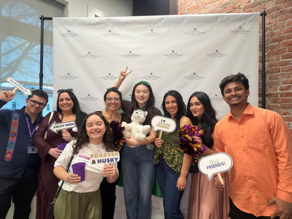 A group of people posing in front of a photo booth holding various public policy related signs