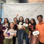 A group of people posing in front of a photo booth holding various public policy related signs