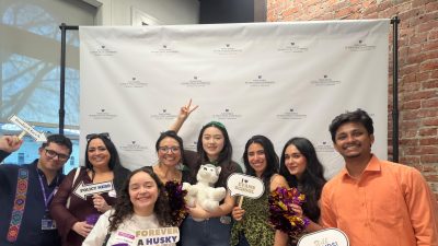 A group of people posing in front of a photo booth holding various public policy related signs